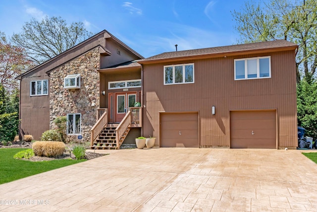 bi-level home featuring stone siding, decorative driveway, and a garage