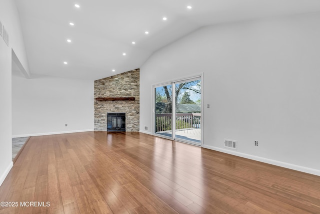 unfurnished living room with a stone fireplace, wood-type flooring, high vaulted ceiling, and visible vents