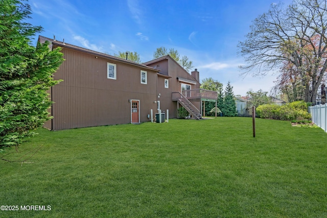 rear view of property with a chimney, a lawn, fence, stairs, and a deck