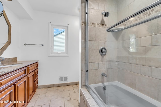 full bathroom featuring tiled shower / bath combo, vanity, visible vents, stone tile floors, and baseboards