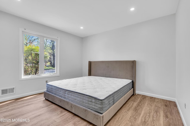 bedroom with baseboards, light wood-type flooring, visible vents, and recessed lighting