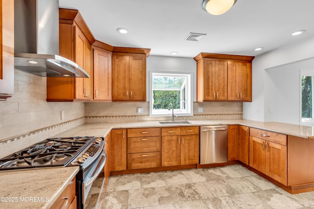 kitchen featuring a peninsula, a sink, wall chimney exhaust hood, visible vents, and appliances with stainless steel finishes