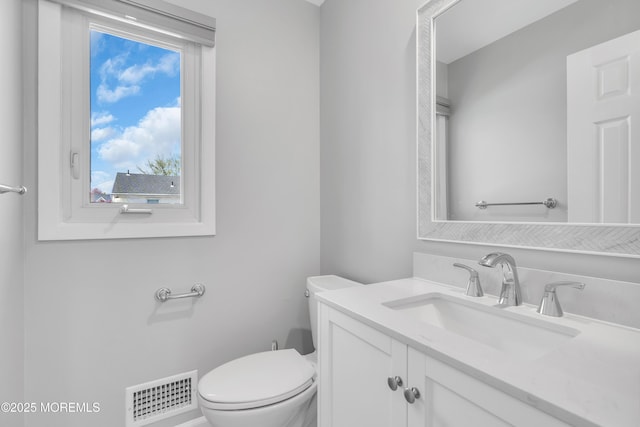 bathroom featuring toilet, vanity, and visible vents