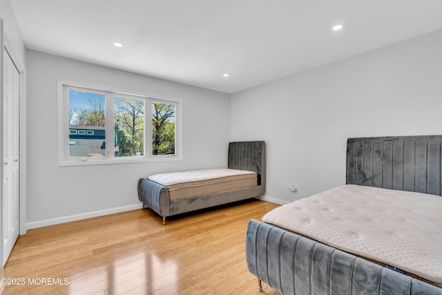 bedroom featuring a closet, light wood-style flooring, baseboards, and recessed lighting