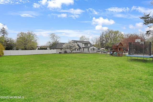 view of yard with a trampoline, a playground, and fence