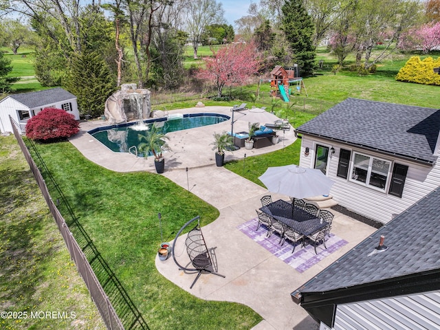 outdoor pool featuring a yard, an outbuilding, a patio, and a playground