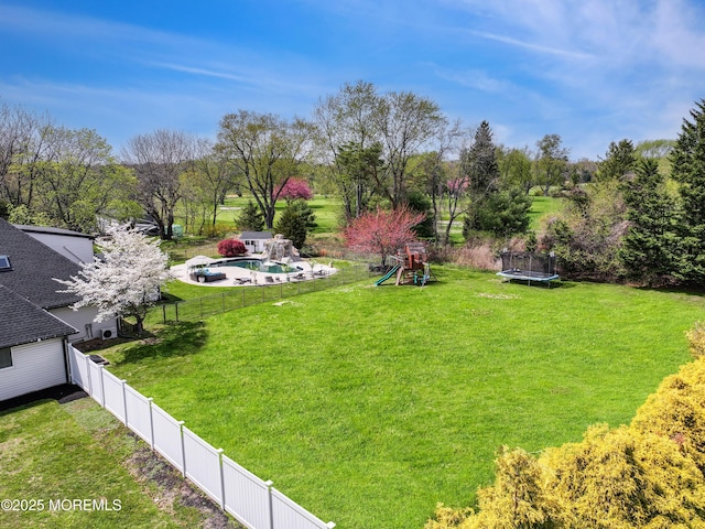 view of yard with an outdoor pool, a fenced backyard, and a trampoline