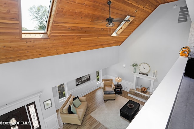 living area with a skylight, a wealth of natural light, wood finished floors, and wood ceiling
