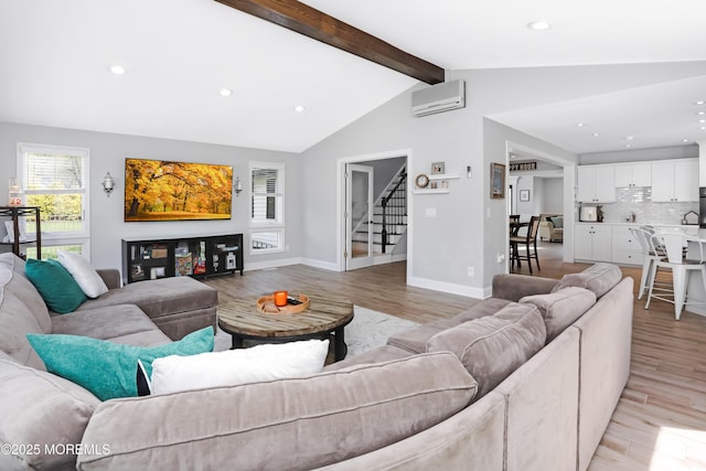 living area featuring a wall unit AC, light wood-style floors, lofted ceiling with beams, recessed lighting, and stairs