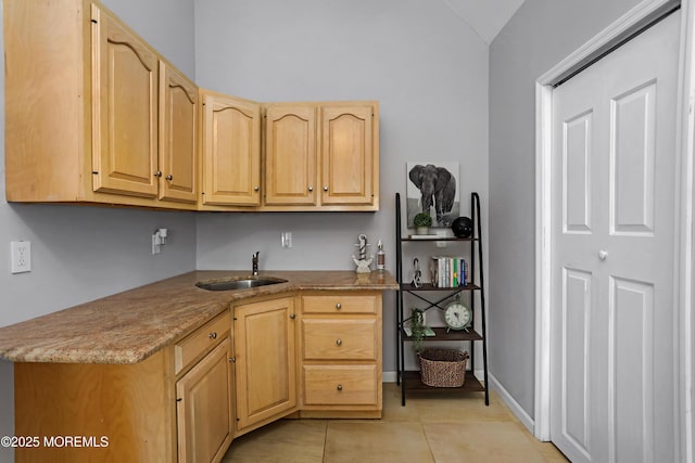 kitchen with light tile patterned floors, light brown cabinets, and a sink