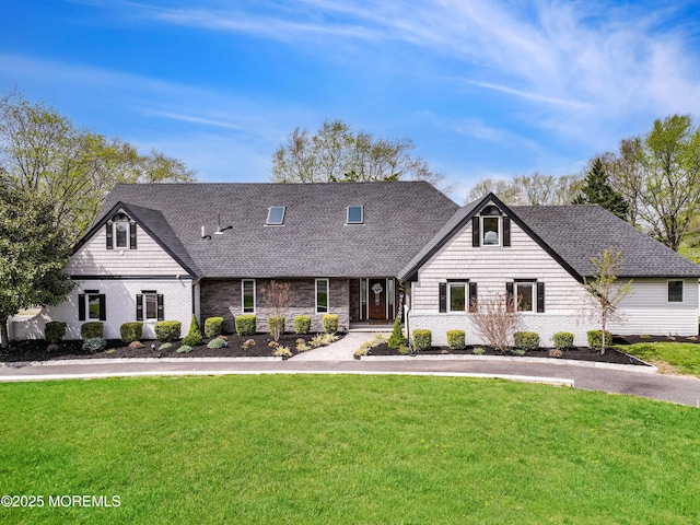 cape cod house featuring roof with shingles and a front lawn