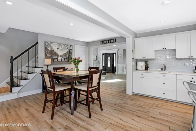 dining space with recessed lighting, light wood-style flooring, baseboards, and stairs