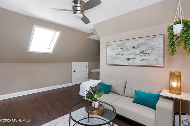 living area with baseboards, wood finished floors, a ceiling fan, and vaulted ceiling with skylight