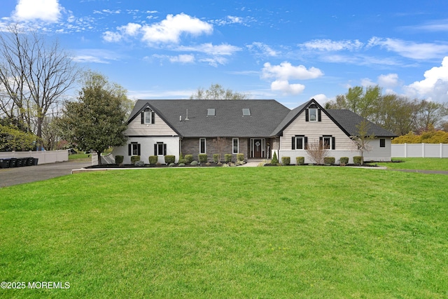 view of front of property with fence, roof with shingles, and a front yard