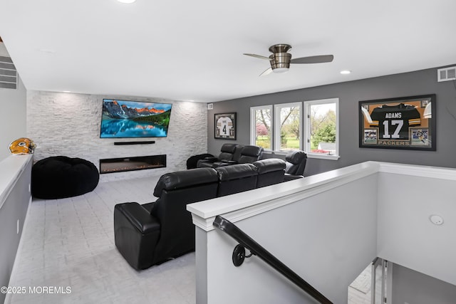 cinema with a ceiling fan and a glass covered fireplace