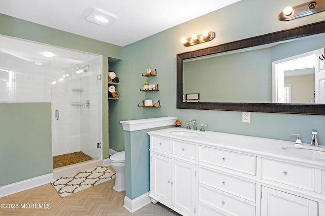 full bath featuring baseboards, a shower stall, double vanity, and a sink