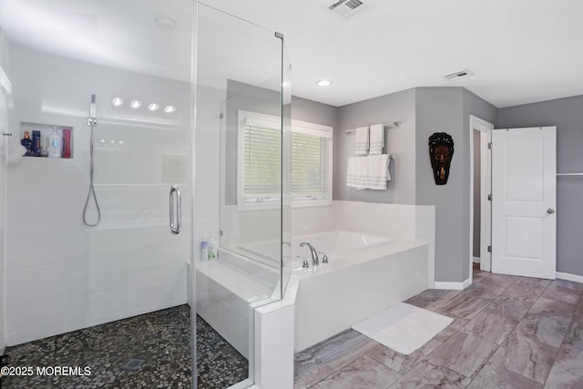 bathroom with a stall shower, visible vents, a bath, and baseboards