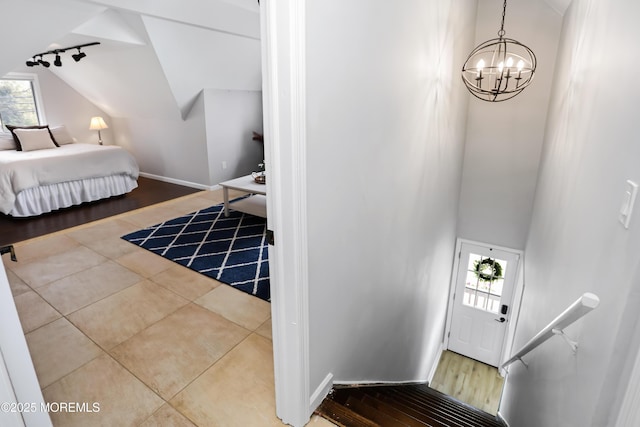 stairway with tile patterned flooring, a notable chandelier, baseboards, and a healthy amount of sunlight