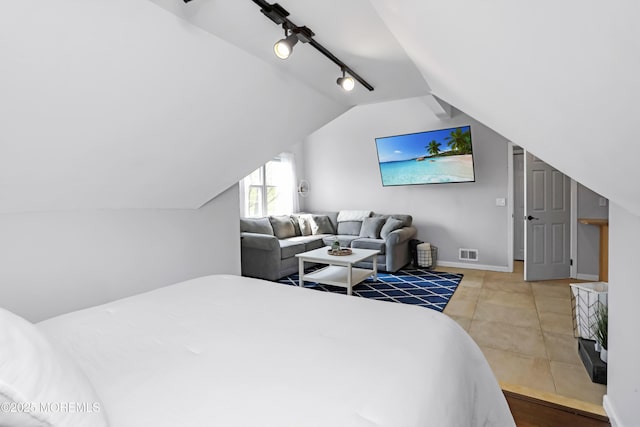 tiled bedroom with baseboards, visible vents, rail lighting, and lofted ceiling
