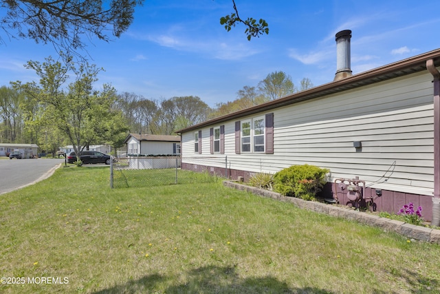 view of side of home with fence and a lawn