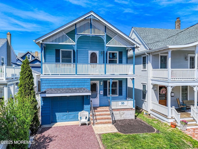 view of front of home with a porch, a garage, a chimney, driveway, and a balcony