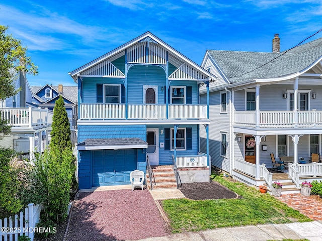 view of front of house with covered porch, a balcony, an attached garage, and driveway
