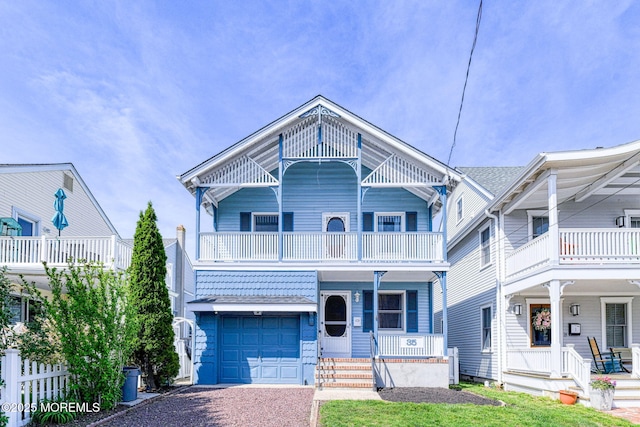 view of front facade featuring a balcony, a porch, driveway, and a garage
