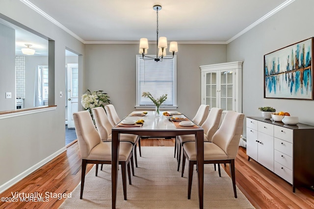 dining room with light wood-style flooring, a chandelier, crown molding, baseboards, and a baseboard radiator
