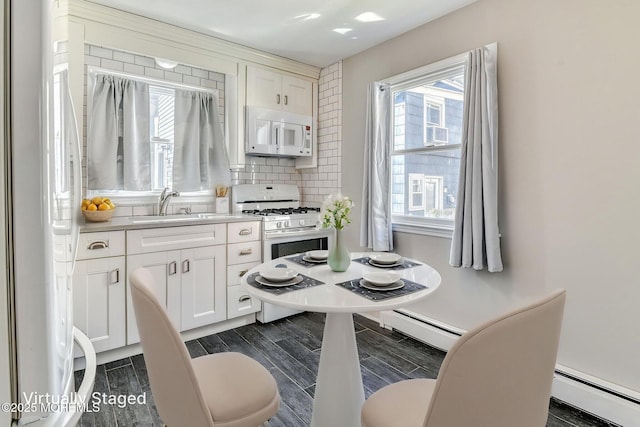 kitchen with white appliances, a baseboard radiator, a sink, and wood tiled floors
