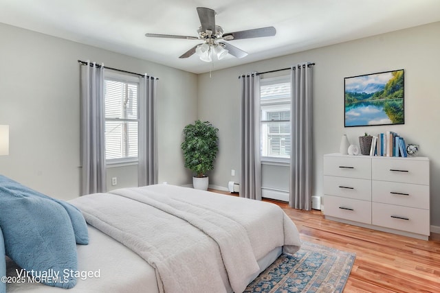 bedroom with light wood-type flooring, a baseboard heating unit, ceiling fan, baseboards, and baseboard heating