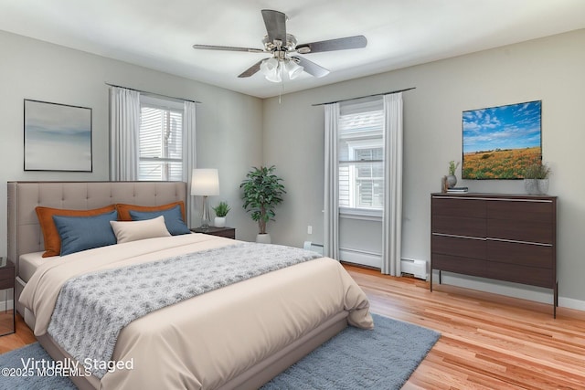 bedroom with light wood-style floors, a baseboard heating unit, a ceiling fan, and baseboards