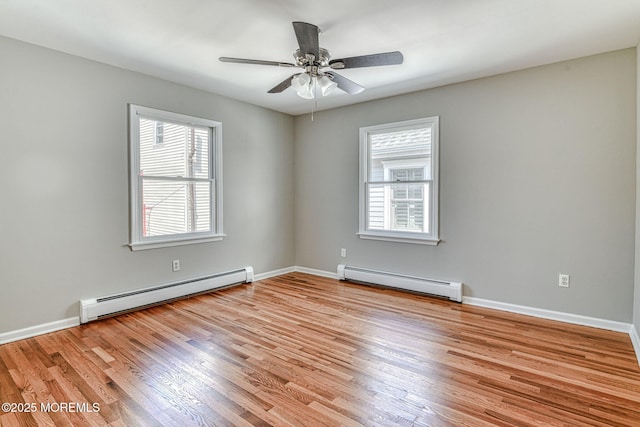 empty room featuring a baseboard heating unit, baseboard heating, healthy amount of natural light, and light wood-style flooring