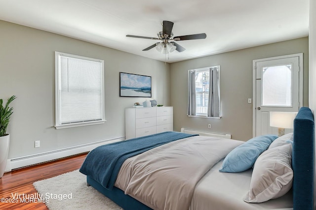 bedroom with baseboard heating, wood finished floors, and a ceiling fan