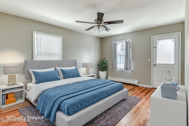 bedroom featuring baseboard heating, light wood finished floors, baseboards, and a ceiling fan