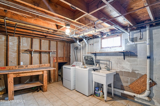 below grade area with washing machine and clothes dryer, light tile patterned flooring, and a sink