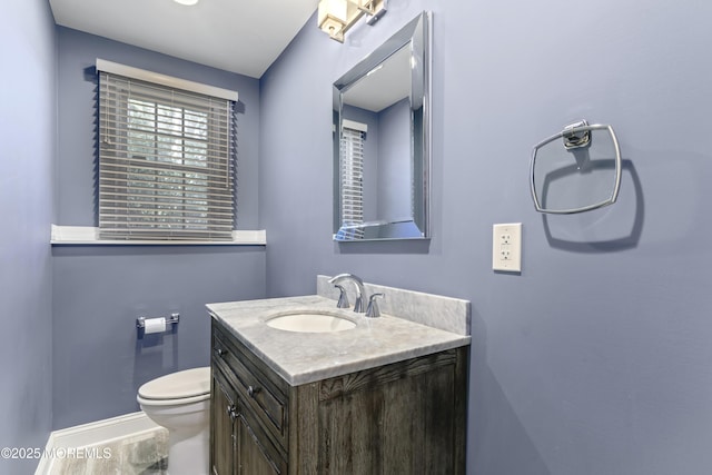 half bathroom featuring baseboards, vanity, and toilet