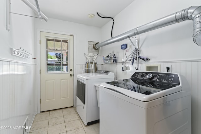 clothes washing area featuring laundry area, light tile patterned floors, and washing machine and dryer