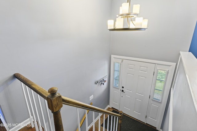 foyer featuring baseboards, a chandelier, and stairway