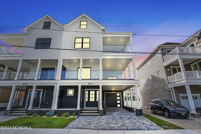 view of front facade featuring an attached garage, driveway, a balcony, and central air condition unit