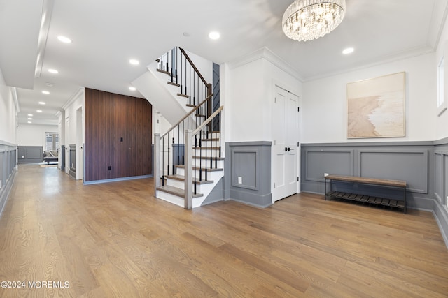 interior space with a decorative wall, crown molding, stairs, and an inviting chandelier