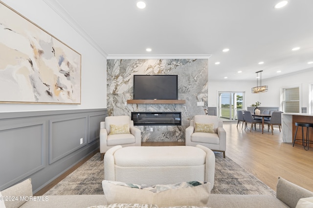 living area featuring wood finished floors, a wainscoted wall, a premium fireplace, ornamental molding, and recessed lighting