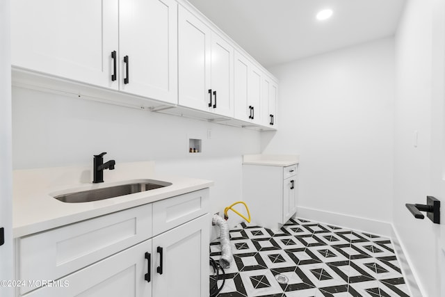 laundry area featuring hookup for a washing machine, a sink, tile patterned floors, cabinet space, and baseboards