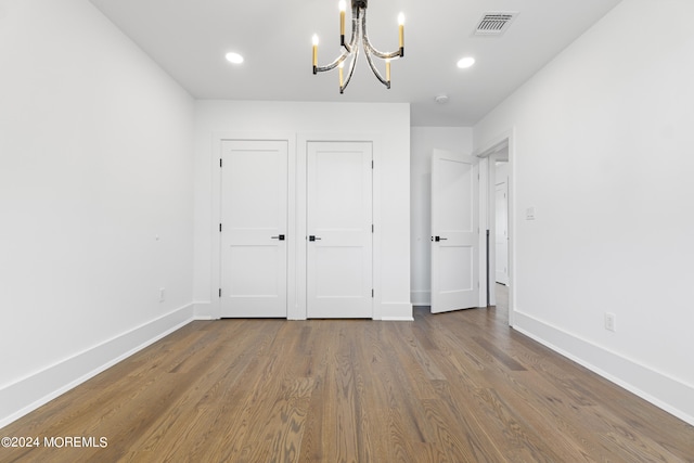 unfurnished bedroom featuring recessed lighting, wood finished floors, baseboards, and an inviting chandelier