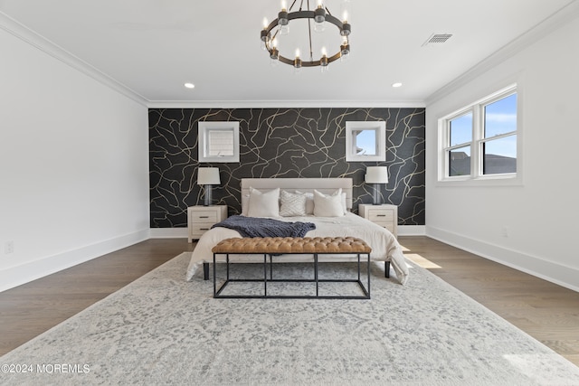 bedroom featuring an accent wall, crown molding, baseboards, a notable chandelier, and visible vents