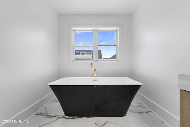 full bathroom with a freestanding tub, baseboards, and marble finish floor