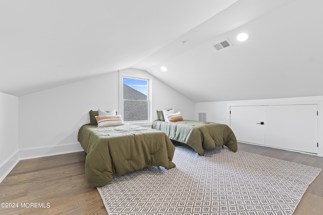 bedroom with lofted ceiling, baseboards, wood finished floors, and visible vents