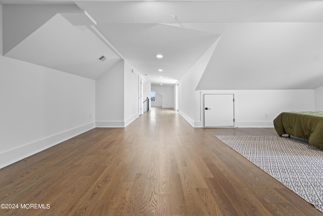 additional living space with vaulted ceiling, wood finished floors, visible vents, and baseboards