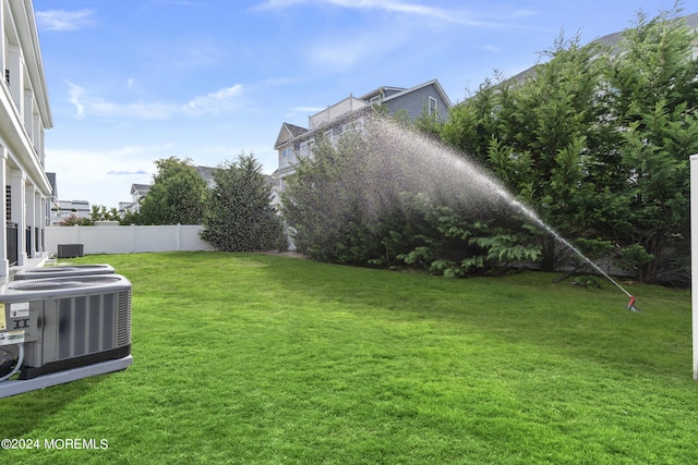 view of yard featuring fence and central AC