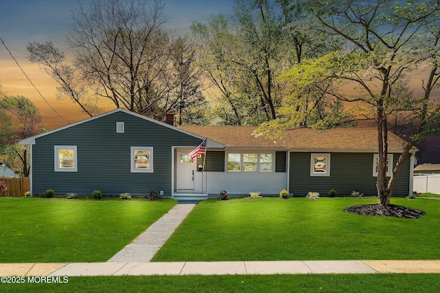 ranch-style house featuring fence, a yard, and brick siding