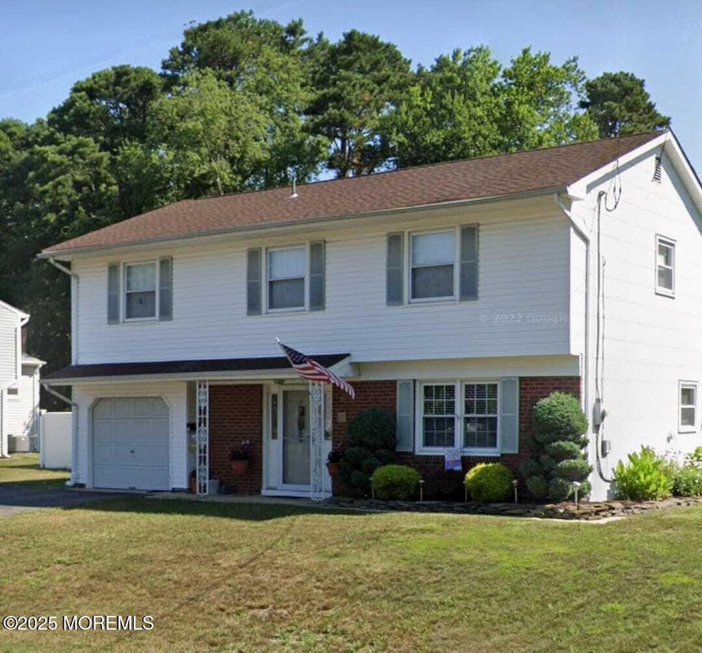 view of front of house with a front lawn, brick siding, and an attached garage